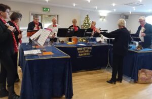 The Greystoke Handbell Ringers provided an upbeat miscellany of Christmas carols and other traditional seasonal music at the December meeting. Members sang along, clapped and rhythmically shook the small sets of handbells which were distributed around the group. Some ladies stepped forward to bravely join the musicians by ringing their large handbells for a couple of the songs. The entertainment followed the delicious Christmas lunch, which was beautifully presented and served at the festively decorated tables. A wonderful start to everyone’s Christmas celebrations.